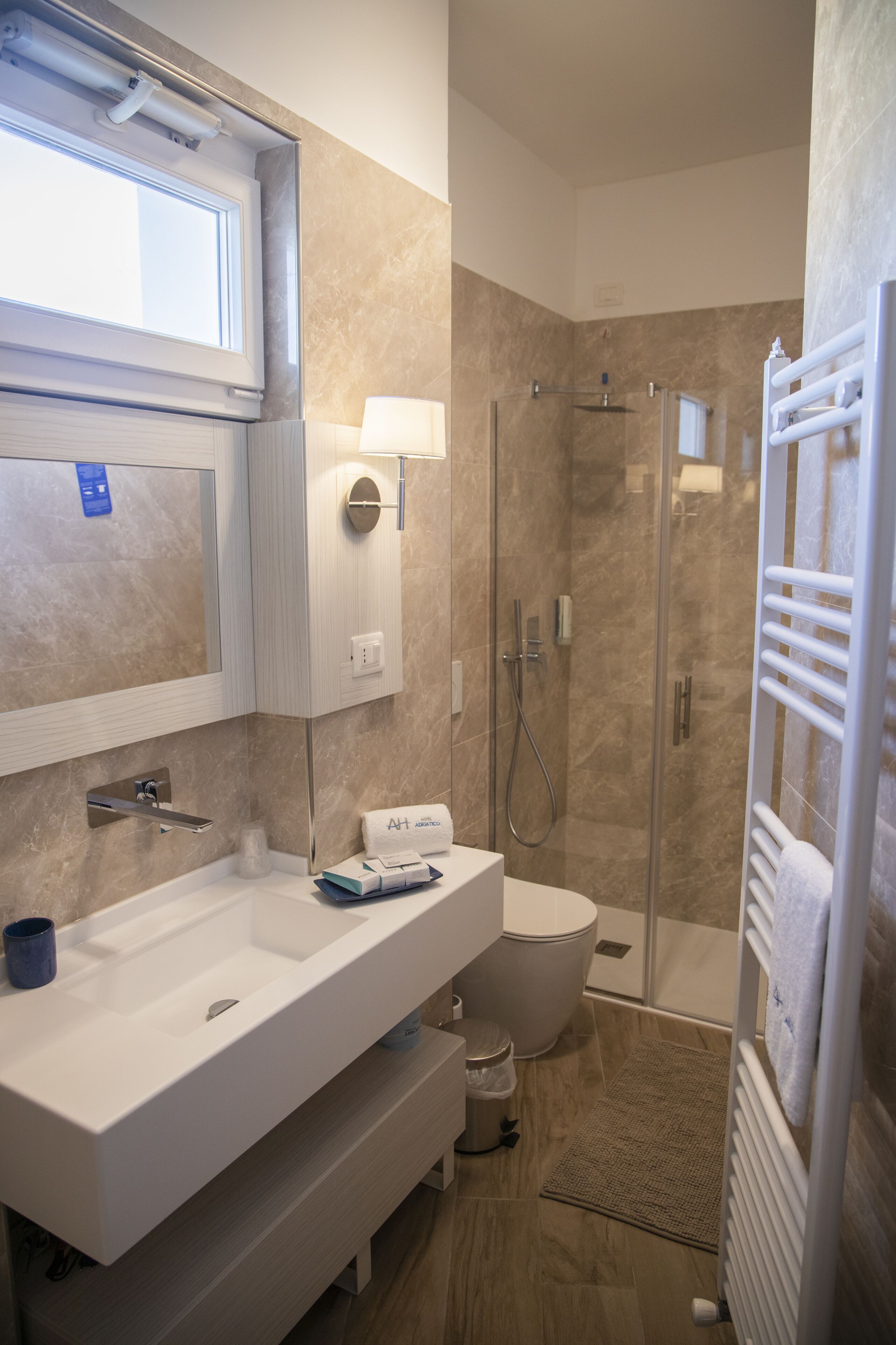 Un baño moderno con un lavamanos grande, inodoro y ducha a ras de suelo.