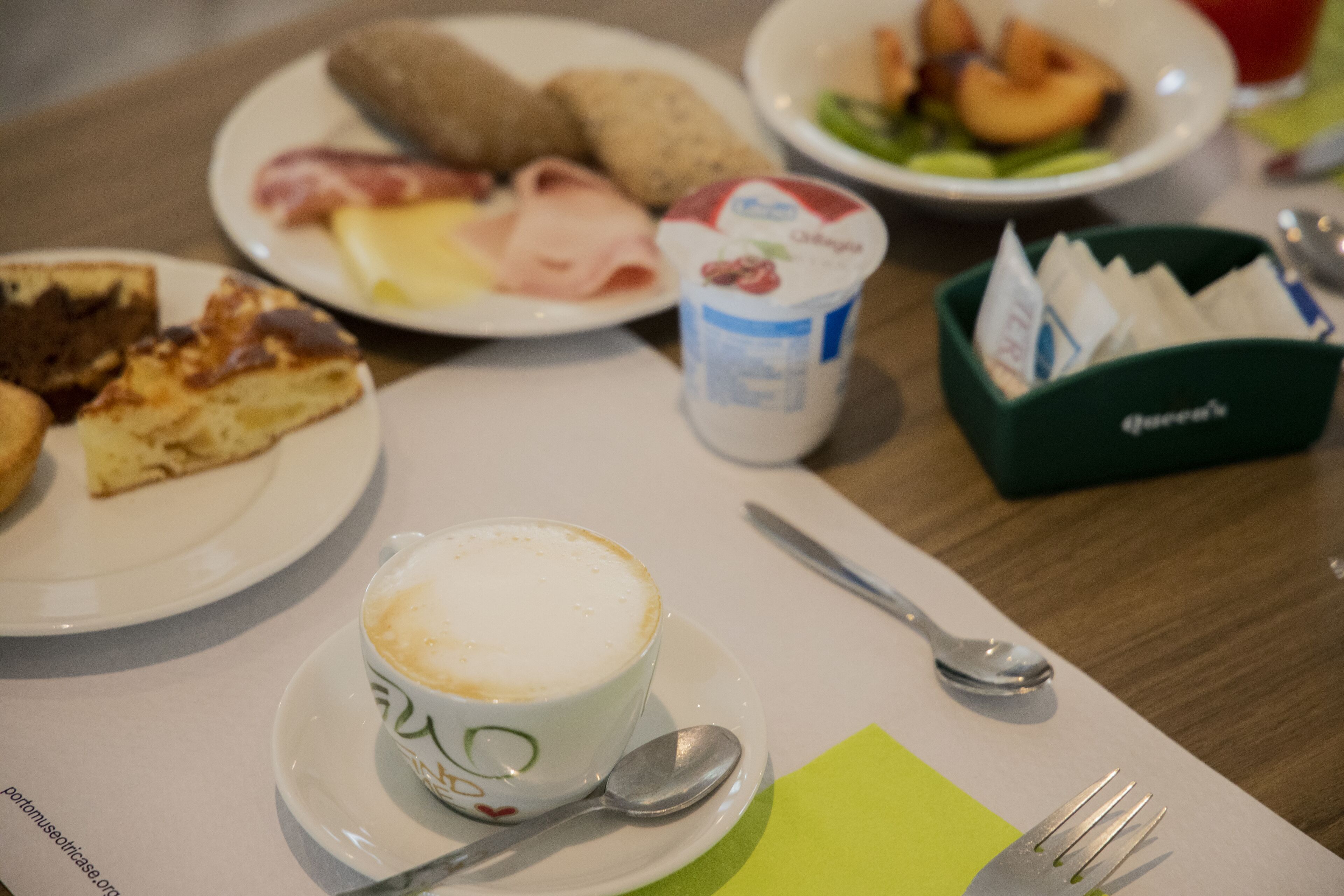 Un desayuno con platos de comida, una taza de café y una servilleta verde.