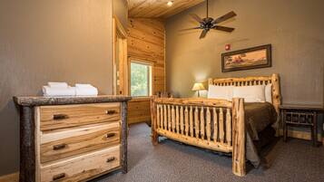 Cozy cabin-style room with a wooden bed, dresser, and ceiling fan.