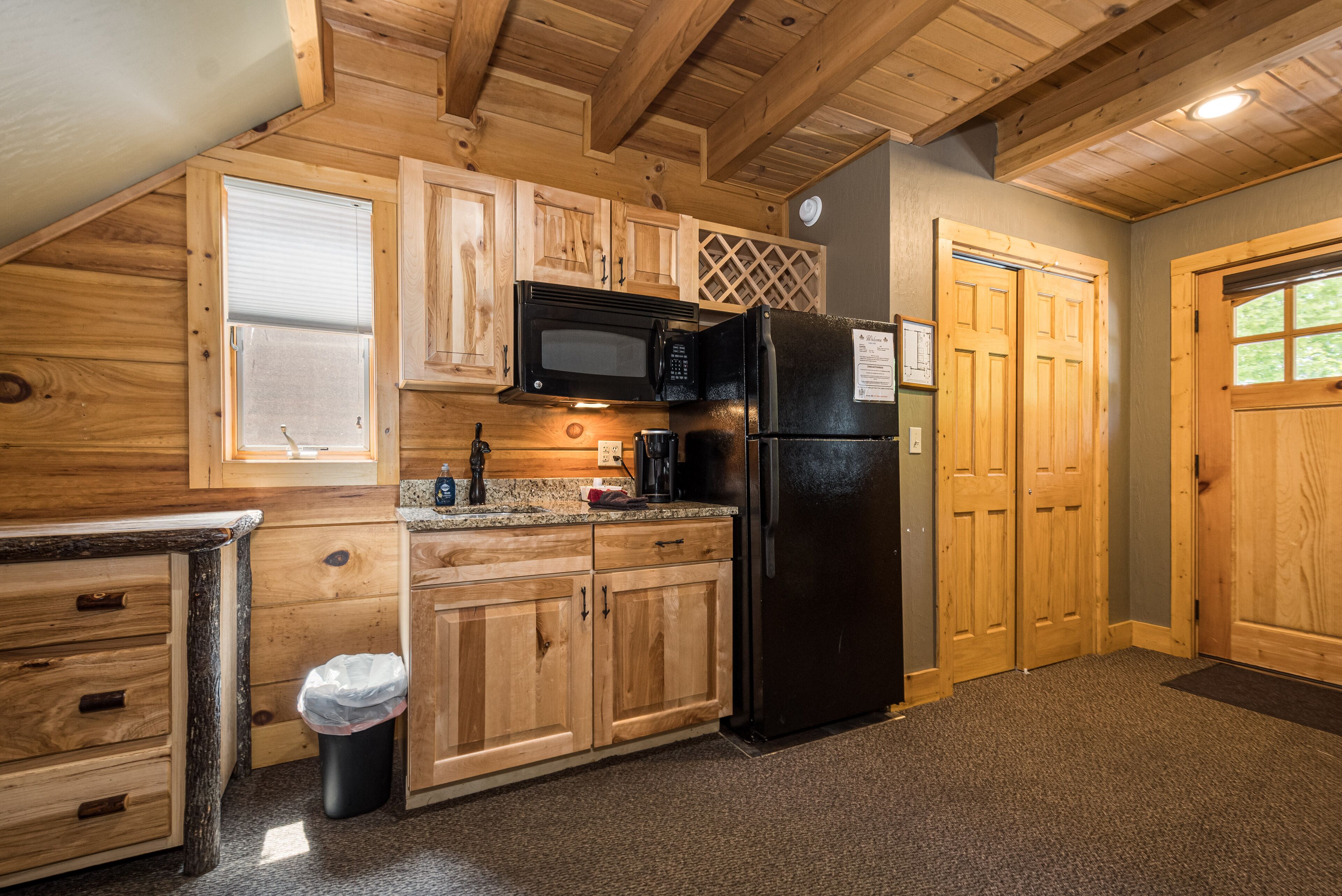 A kitchen with wooden cabinets, a black microwave, and a refrigerator.