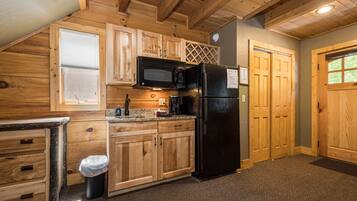 A kitchen with wooden cabinets, a black microwave, and a refrigerator.