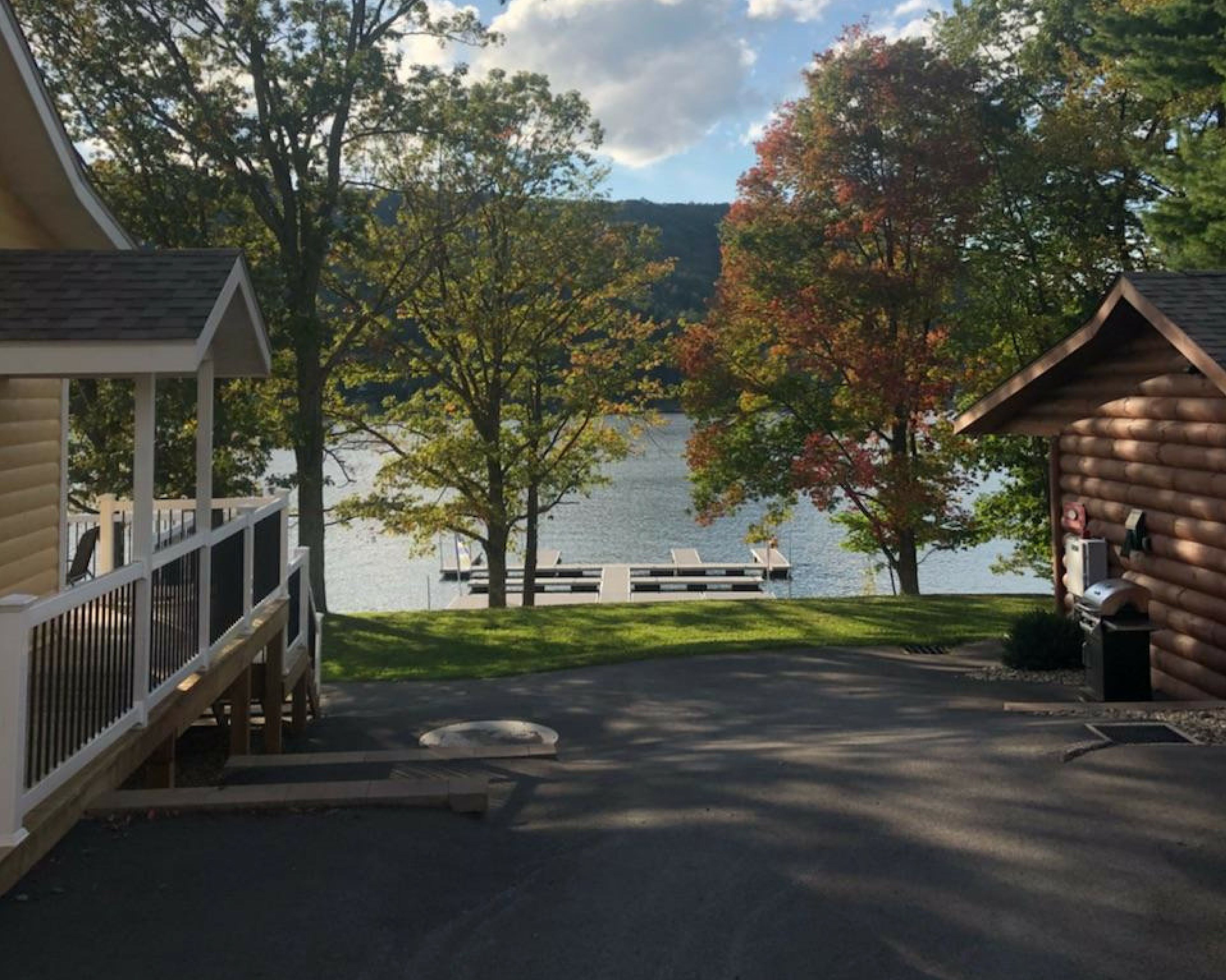A lakeside cabin with a dock, a covered deck, and a grassy area leading to the water.
