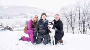 Tres personas y un perro en un paisaje invernal nevado.