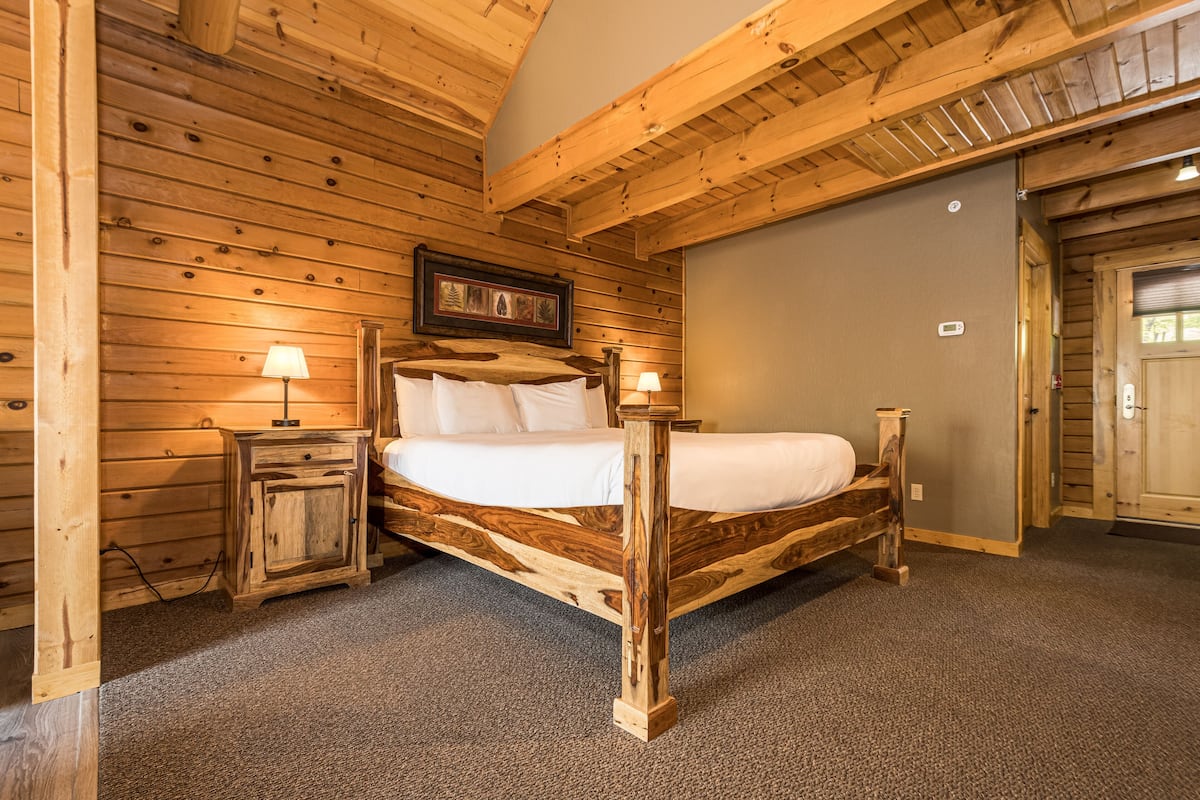 Ein Schlafzimmer mit Holzwänden, einem Bett, Nachttischen und einem gerahmten Bild an der Wand.