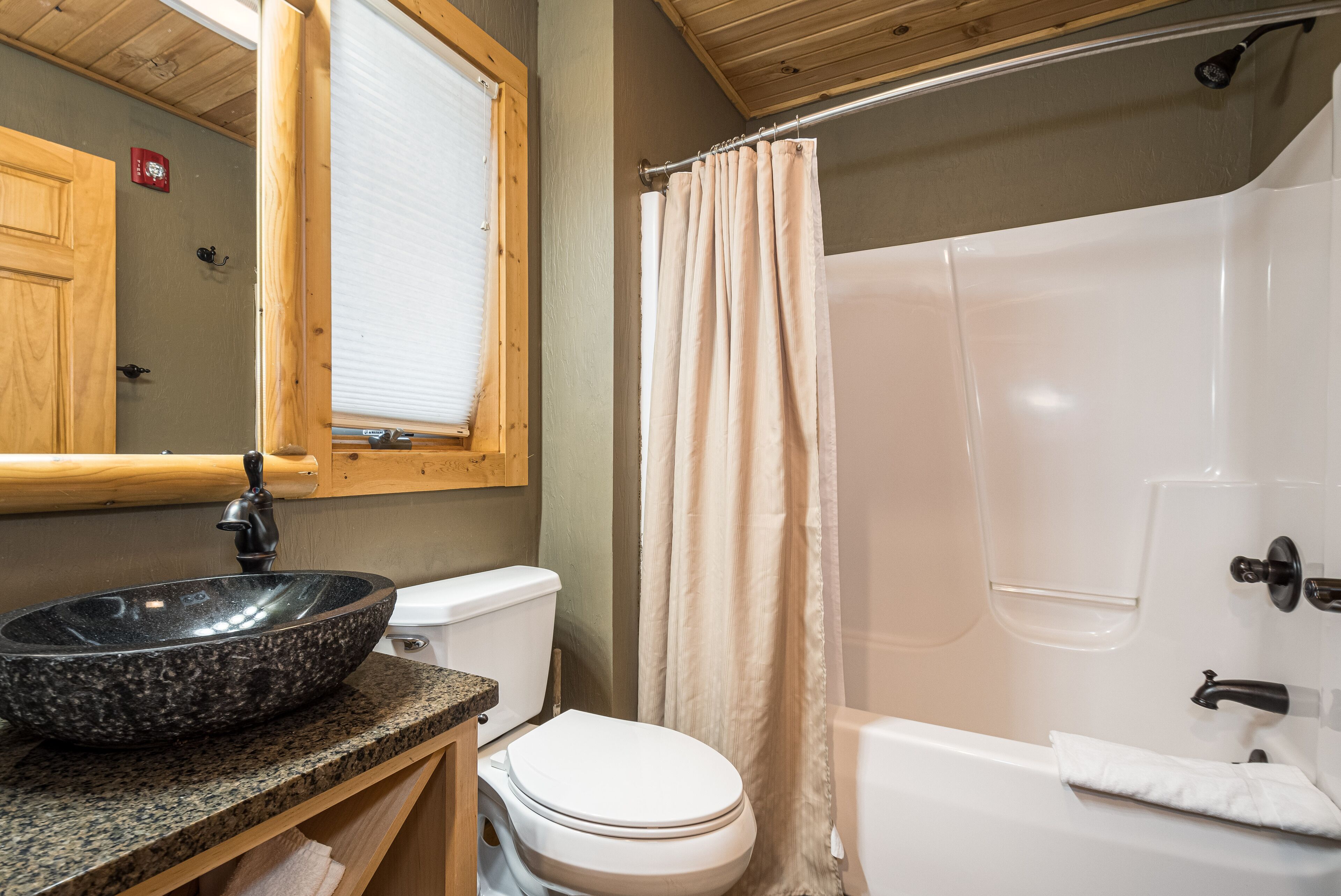 A bathroom with a stone sink, toilet, and bathtub.