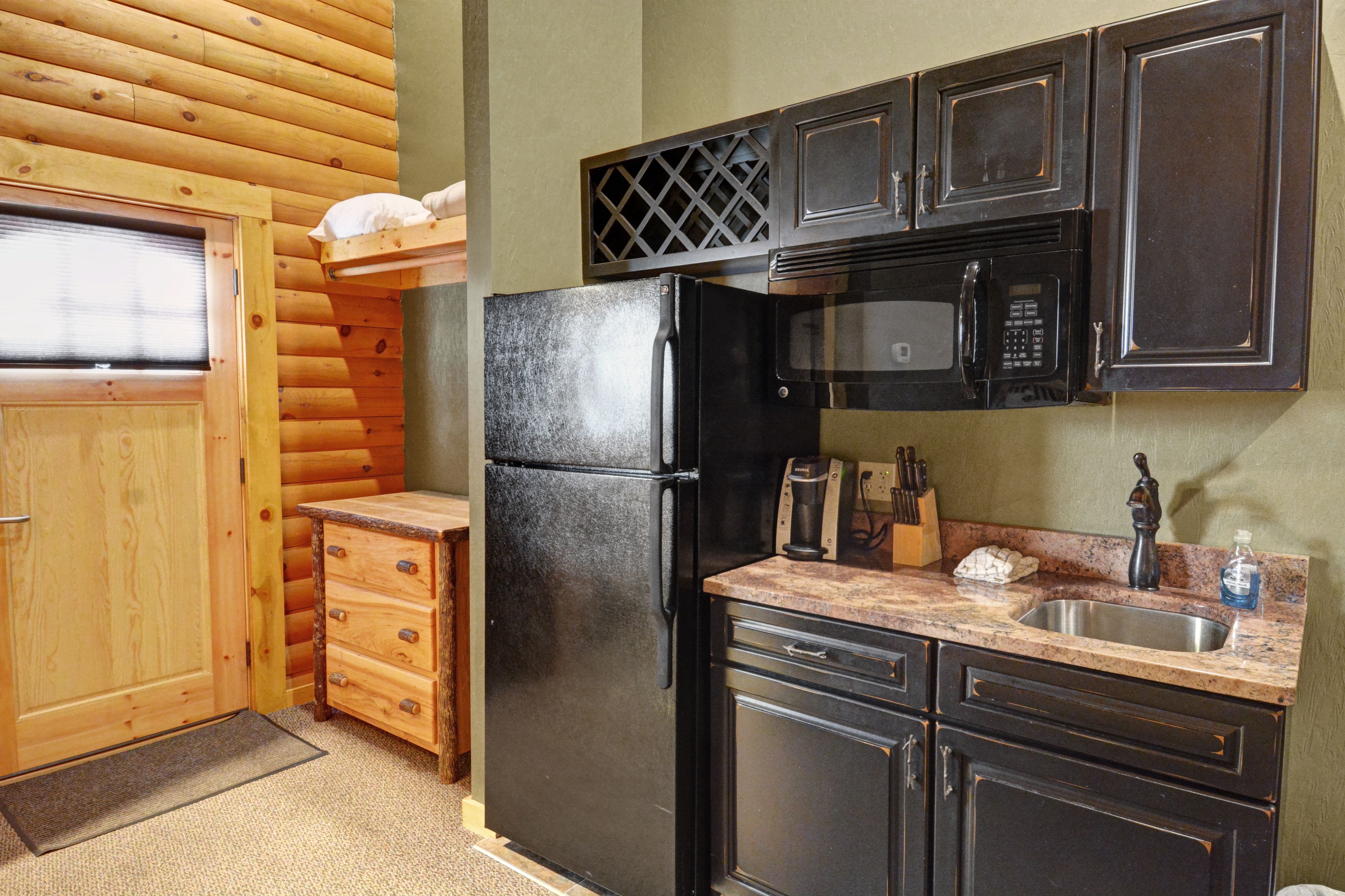 A compact kitchen with a refrigerator, microwave, and wooden cabinets.
