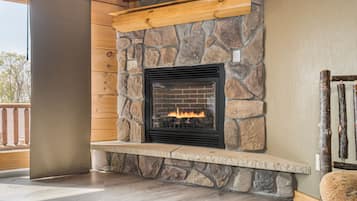 Une cheminée en pierre avec un feu de bois, un banc en bois et un téléviseur fixé au-dessus.