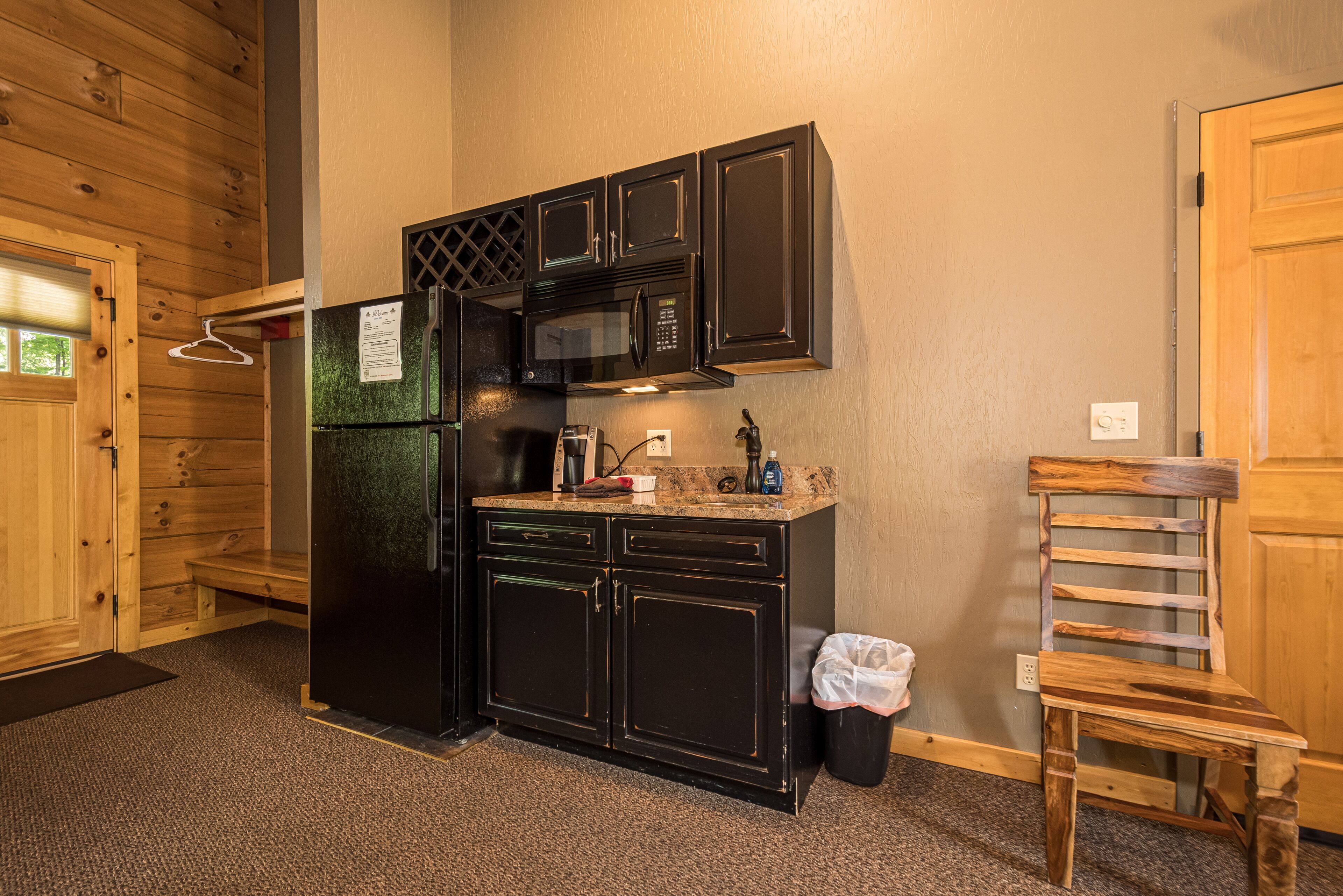 A compact kitchen with black cabinets, a microwave, and a refrigerator.