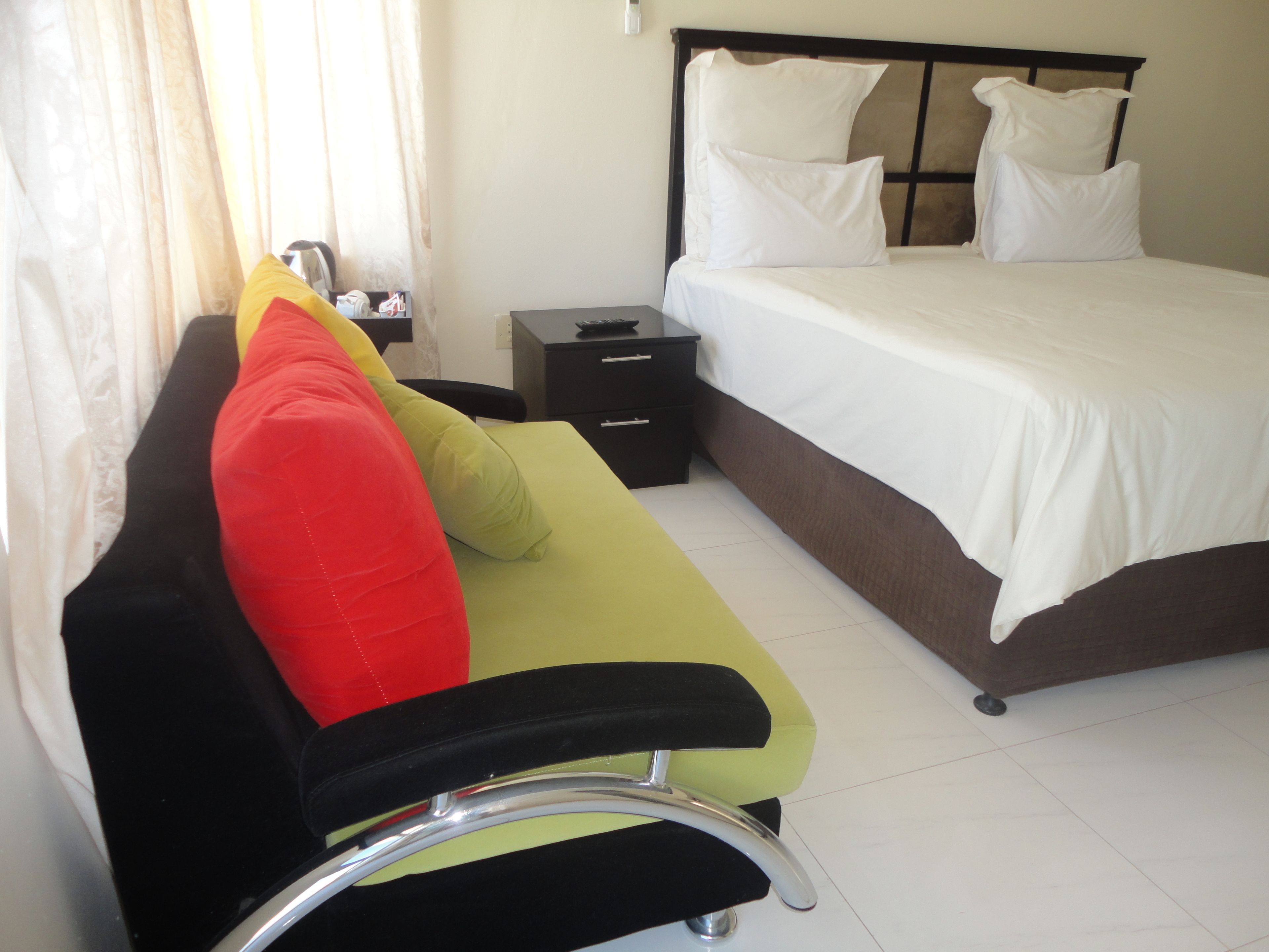 Una habitación de hotel con una cama, una mesita de noche, un escritorio y una silla.