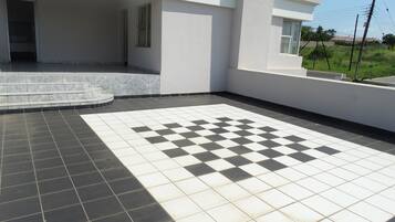 Un edificio moderno con un patrón de piso a cuadros, una escalera que lleva a una zona cubierta y vistas a un campo de césped.