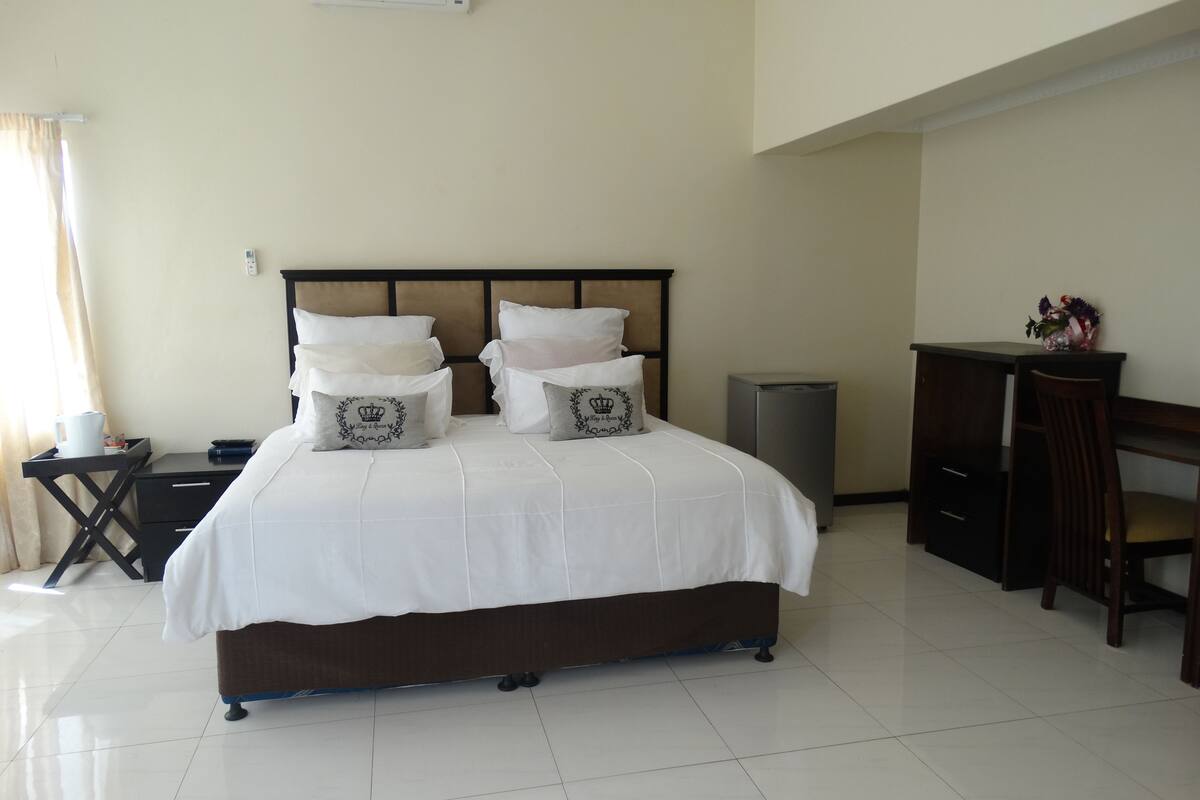 A neatly arranged hotel room with a large bed, bedside tables, a desk, and a chair.