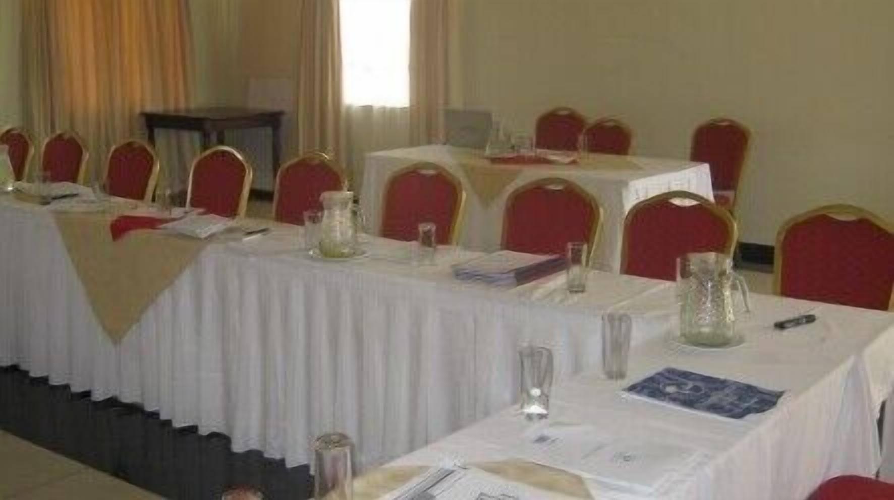 A conference room with tables set for a meeting, red chairs, and a white tablecloth.