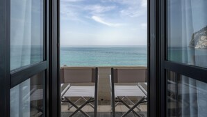 A balcony with two white chairs facing a sea view.