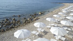 A beach with white umbrellas and lounge chairs.