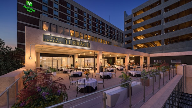 Hotel gevel met een terras en een eethoek, buiten zitplaatsen en een bord met 'The Imperial Terrace'.