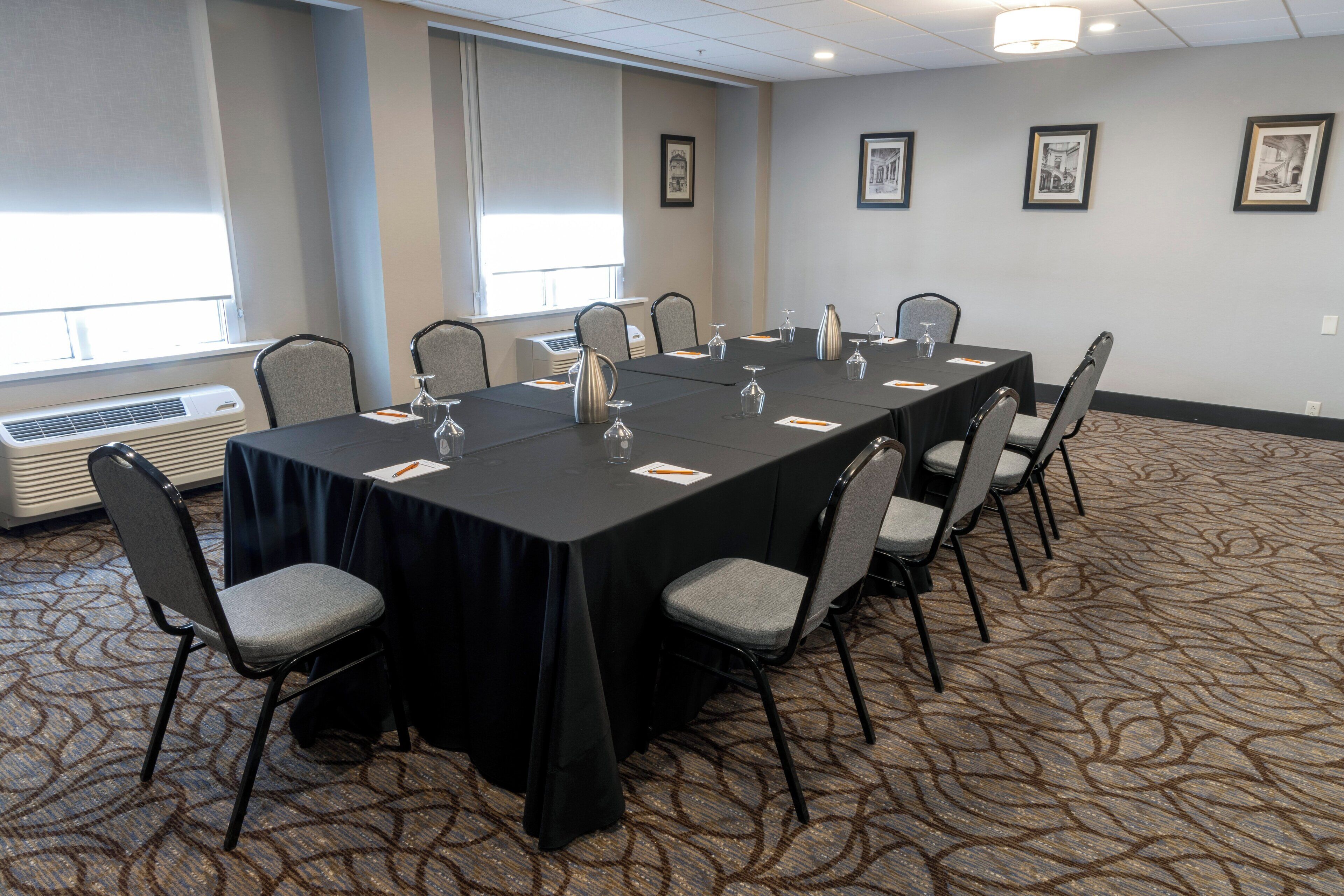 A conference room with a long table, chairs, and framed pictures on the wall.