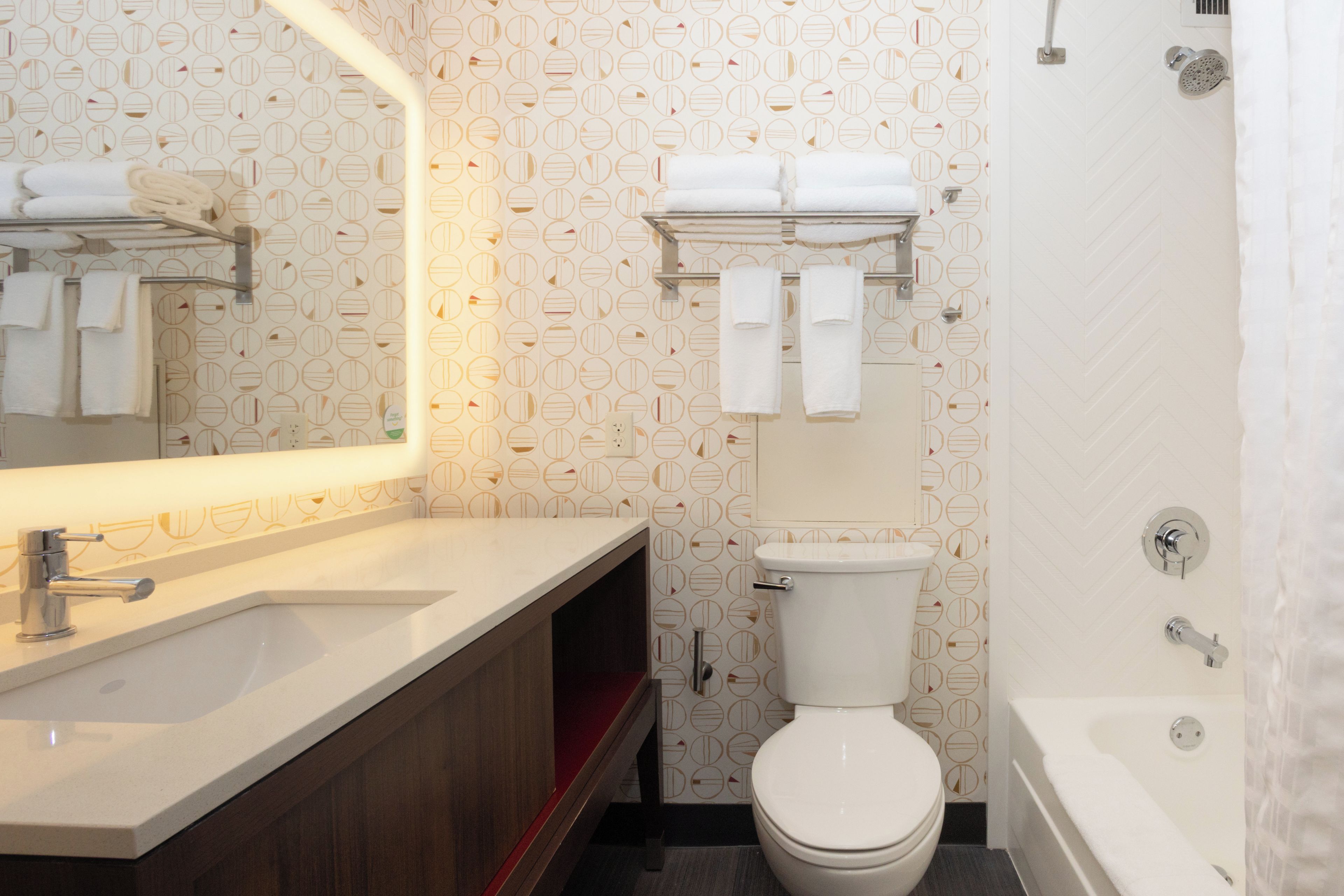 Un baño moderno con lavamanos, espejo, inodoro y bañera blancos.