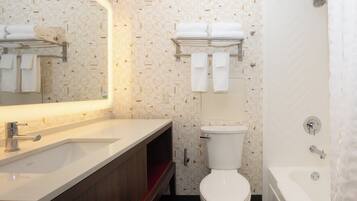 Un baño moderno con lavamanos, espejo, inodoro y bañera blancos.
