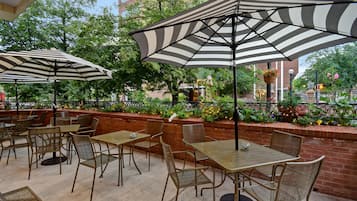 Un patio al aire libre con sombrillas a rayas, mesas y sillas de mimbre.
