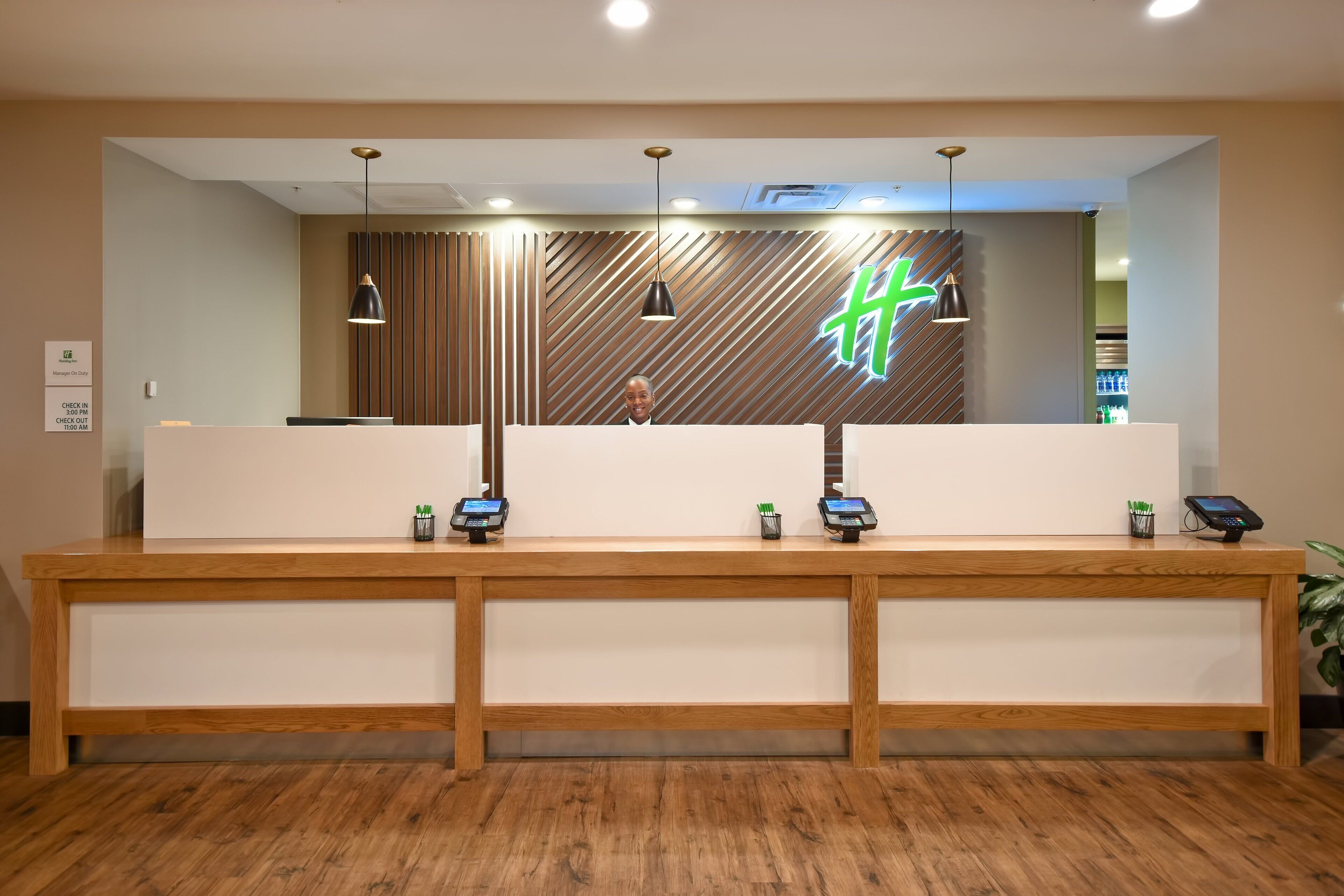 A reception desk with a modern design, featuring a wooden finish and a large illuminated 'H' sign.