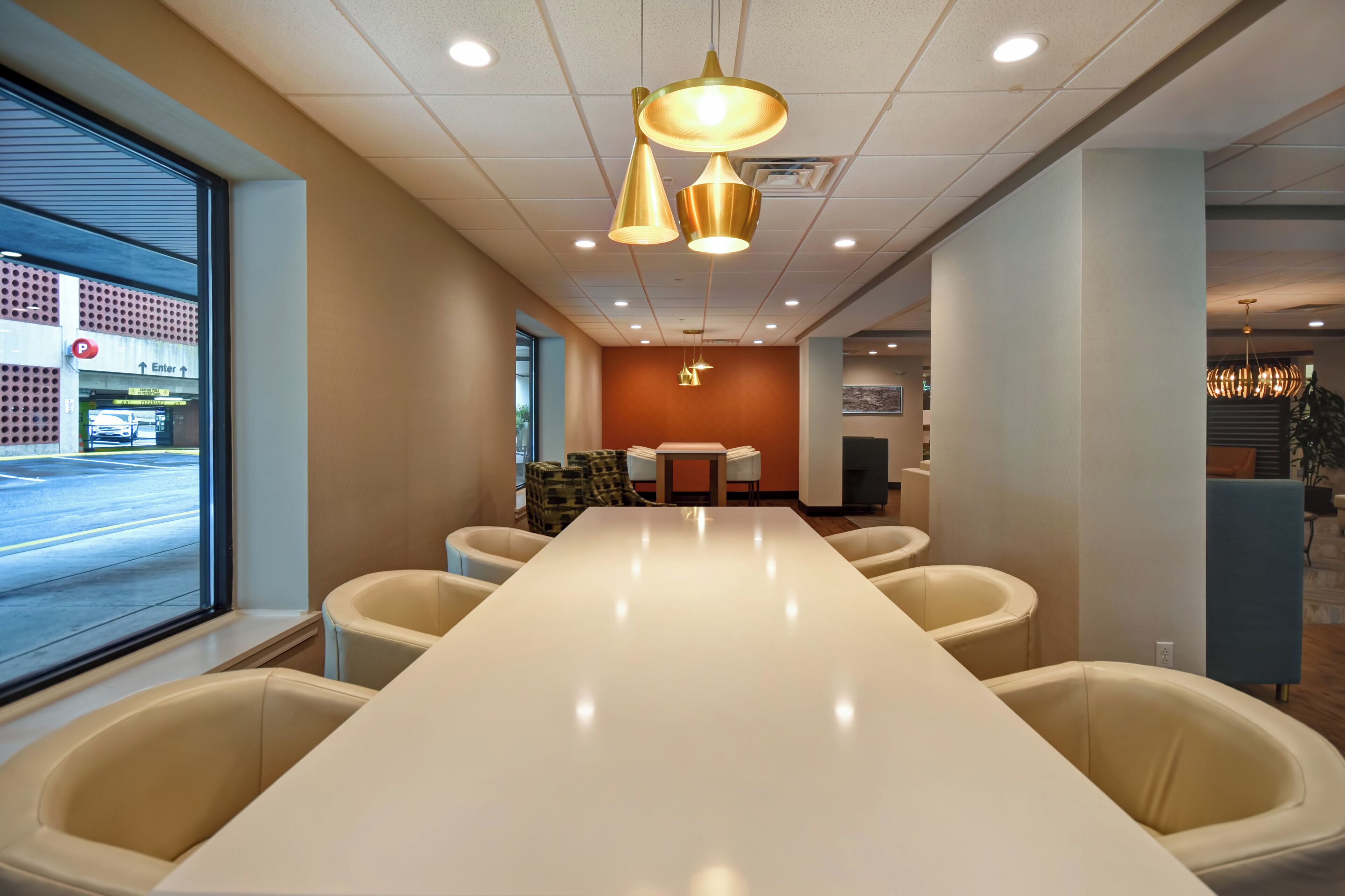 A conference room with a long table and chairs, a large window, and a ceiling with recessed lighting.