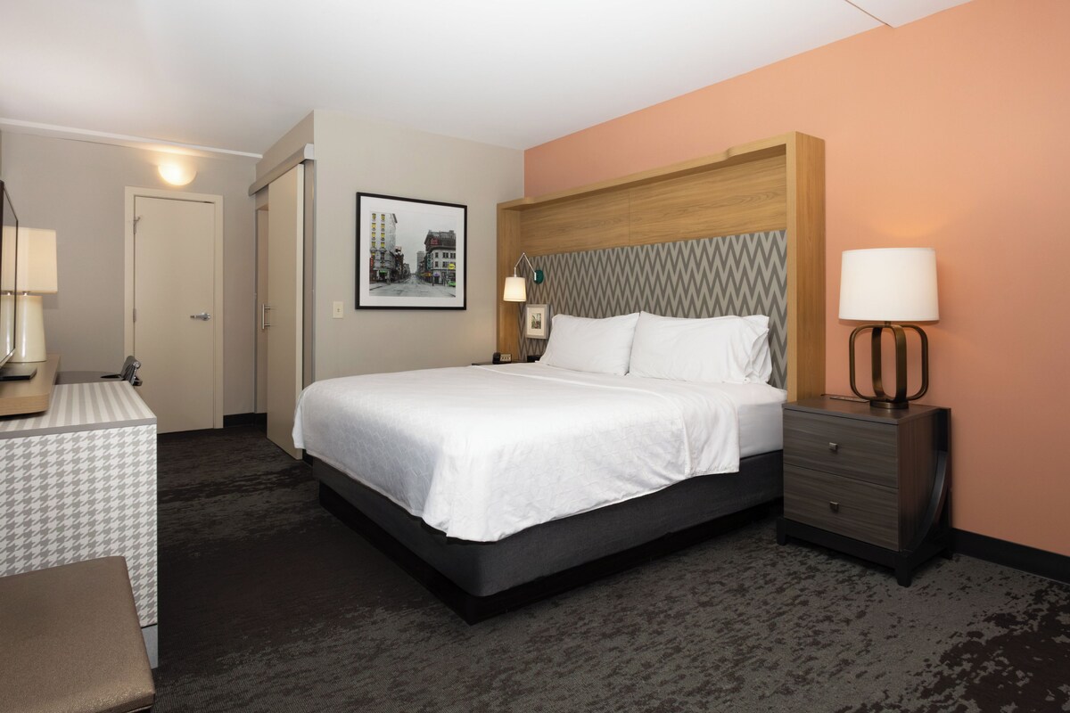 A hotel room with a bed, bedside tables, a desk, and a chair.