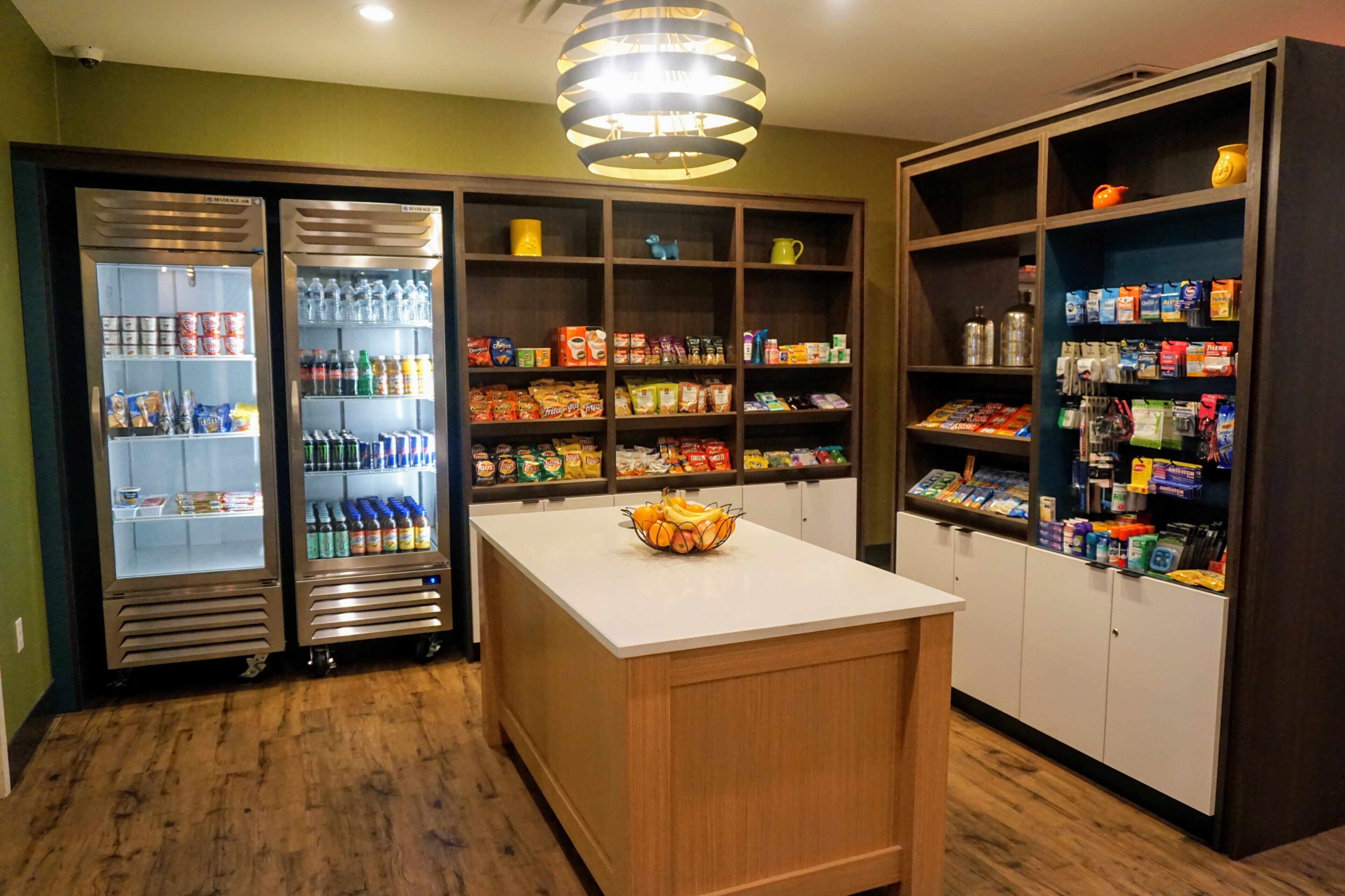 A kitchenette with a refrigerator, pantry, and a fruit bowl on the counter.