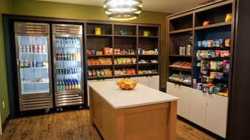 A kitchenette with a refrigerator, pantry, and a fruit bowl on the counter.