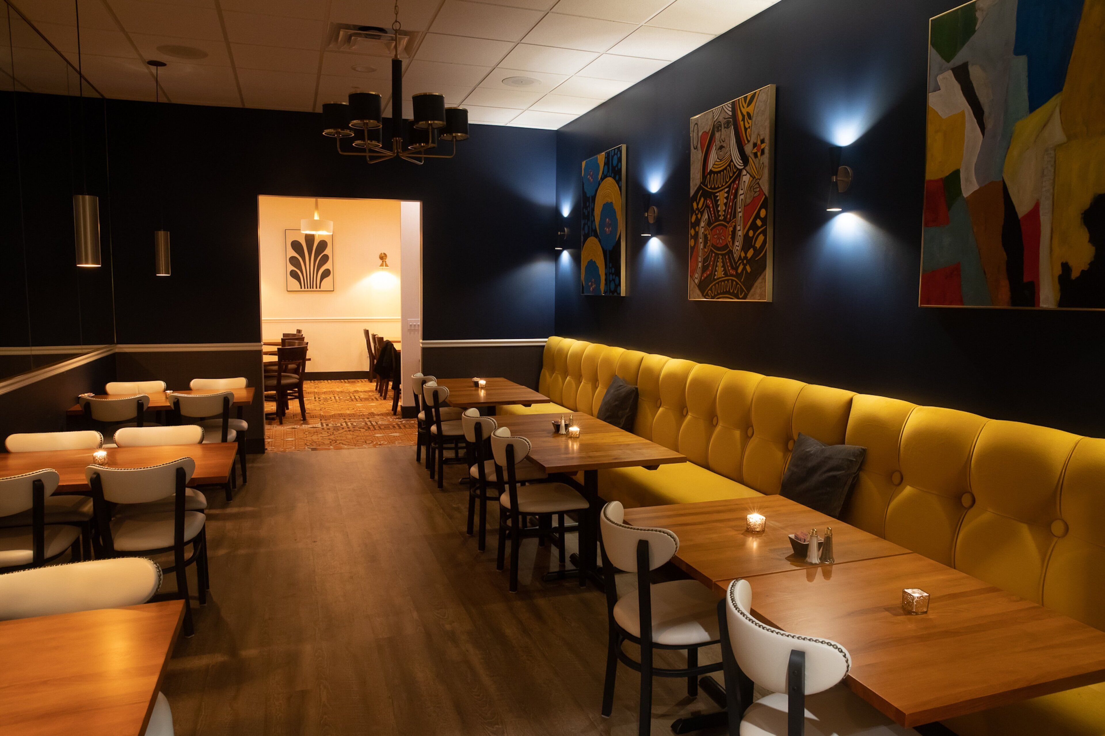A restaurant with a long wooden table, yellow cushioned bench, and modern decor.