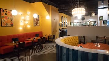Un restaurante con un sofá rojo, mesas para comer y una zona de bar.