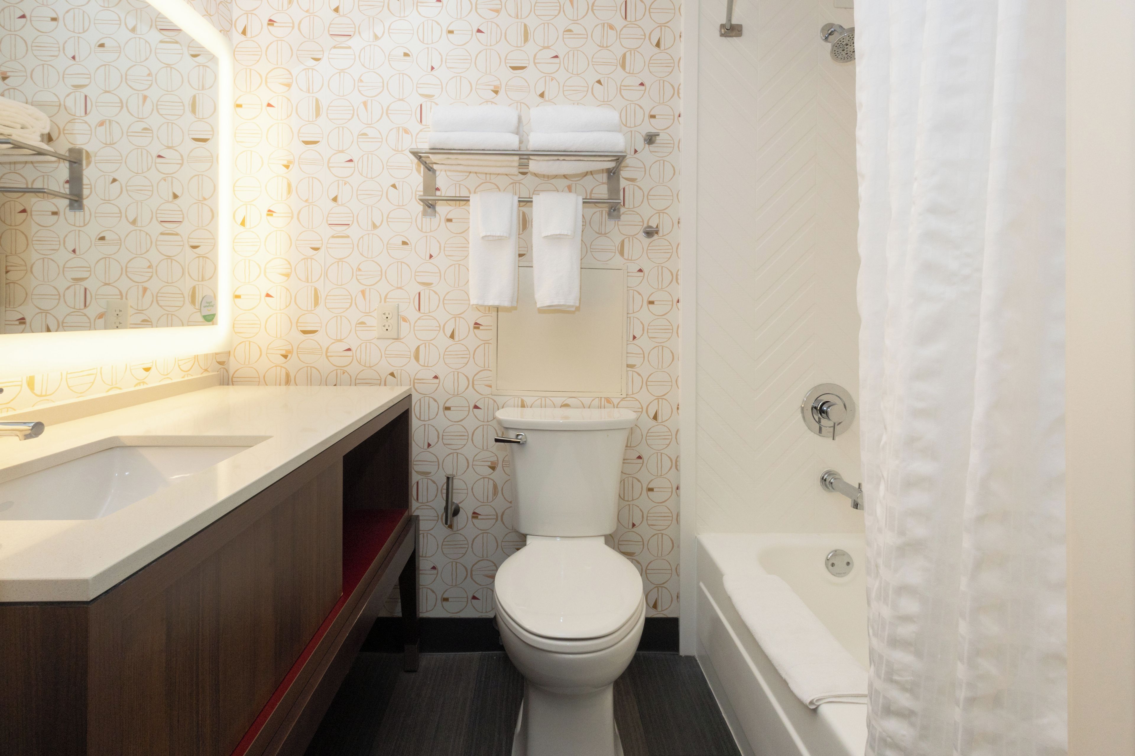 A bathroom with a toilet, a sink, a shower, and a mirror.
