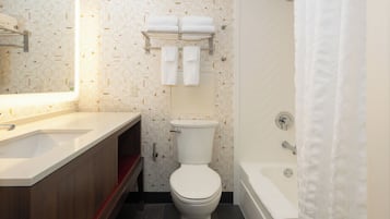 A bathroom with a toilet, a sink, a shower, and a mirror.