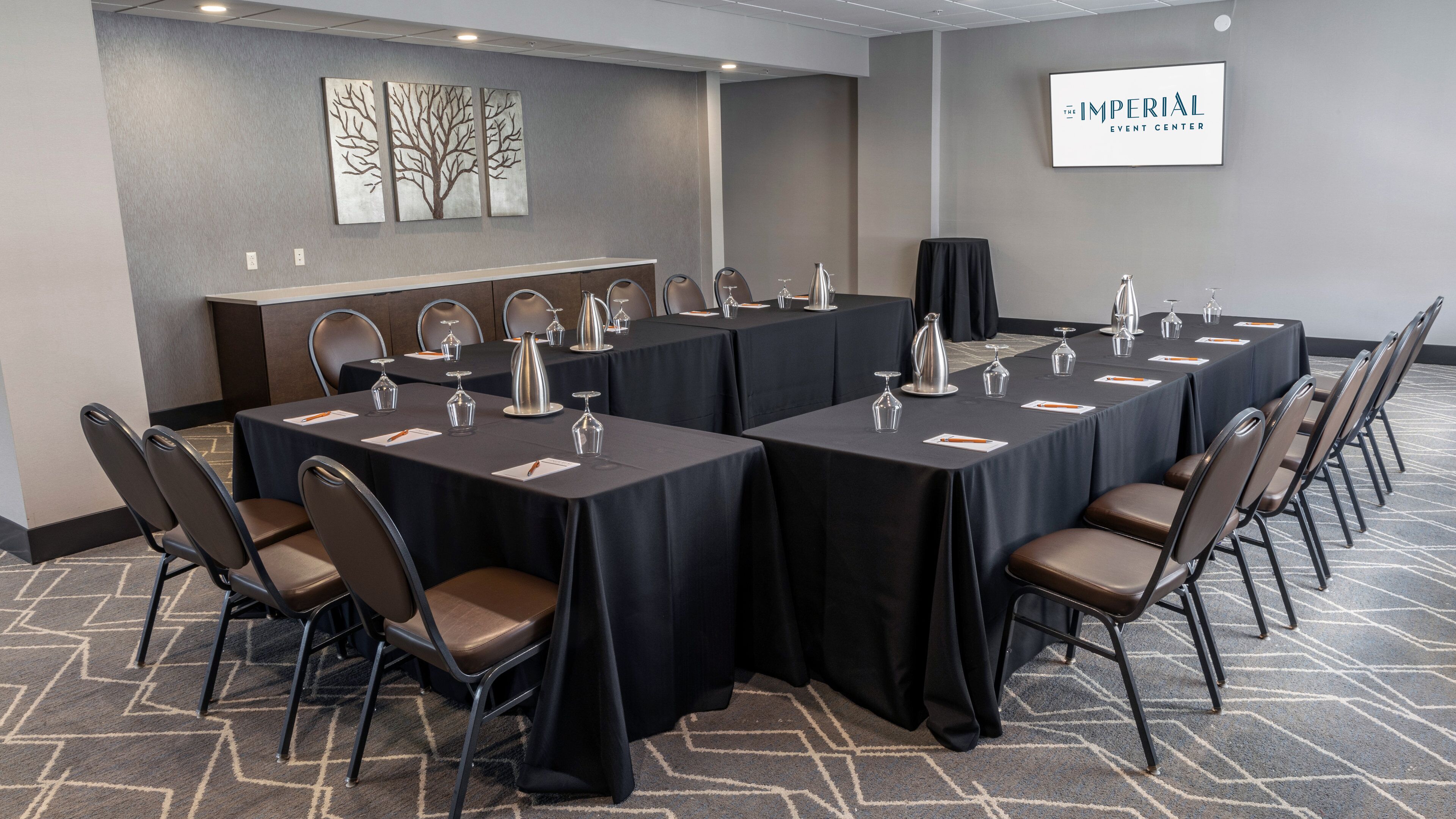 Un salón de conferencias con largas mesas, sillas y un cartel que dice 'The Imperial Event Center'.