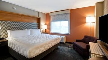 Quarto de hotel com uma cama grande, televisão, escrivaninha, cadeira e janela com vista.