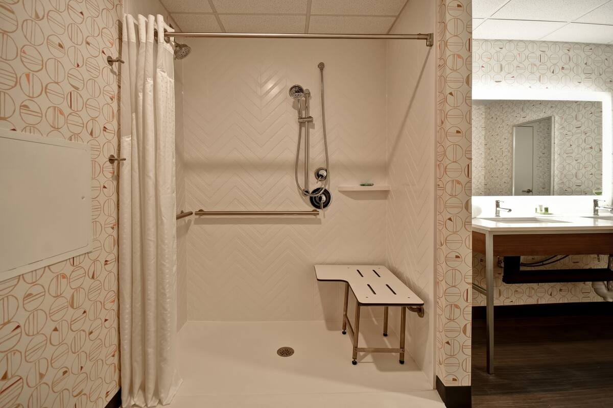 A bathroom with a shower, a sink, and a mirror.