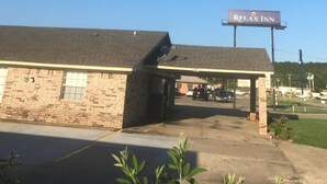 Un edificio de ladrillo con un letrero que dice 'Relax Inn' y un área de estacionamiento techada.