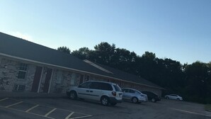 Un estacionamiento con varios coches y un edificio de fachada de ladrillo.