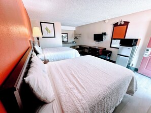 A hotel room with two beds, a desk, a chair, a television, a refrigerator, and a microwave.