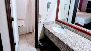 Un baño con lavamanos, espejo y zona de ducha.