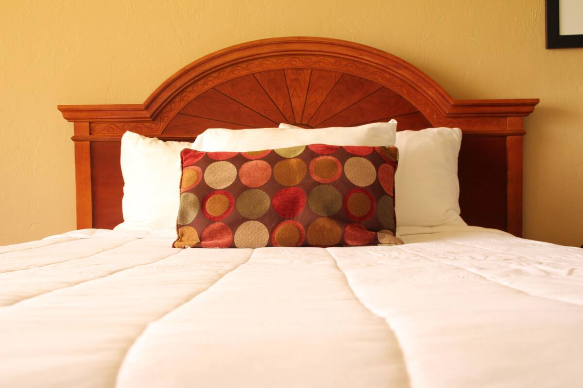 Una cama bien hecha con un cojín estampado y un cabecero de madera.