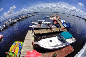Een jachthaven met boten afgemeerd aan houten steigers, een aangemeerd speedboot met een blauw dak en een kleurrijke opblaasboot.