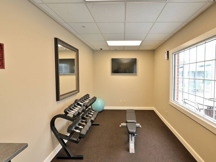 Un gimnasio con equipo de ejercicio, un espejo grande y una ventana con vistas.