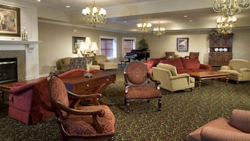 A spacious lobby with a fireplace, multiple seating areas, and a grand chandelier.