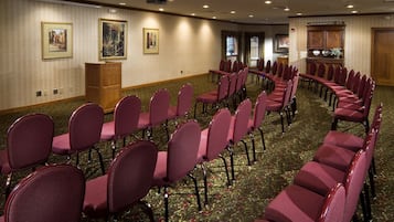 A conference room with rows of chairs, a podium, and framed artwork on the walls.