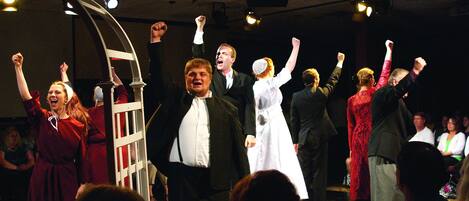 A group of people on a stage with raised arms, possibly in a performance or celebration.