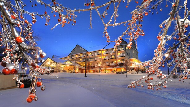 A multi-story hotel with a snow-covered ground, large windows, and balconies. - Carlisle Inn Sugarcreek (Sugarcreek)