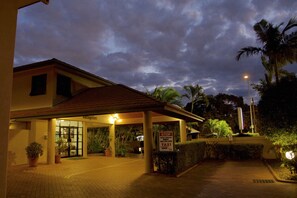 A hotel entrance with a covered waiting area, a sign indicating a taxi zone, and a palm tree in the background. - Pegasus Motor Inn and Serviced Apartments (Hamilton)