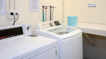 A laundry area with a commercial dryer and a front-loading washing machine.