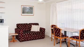 A compact living space with a sofa, two chairs, a small table, and a microwave.
