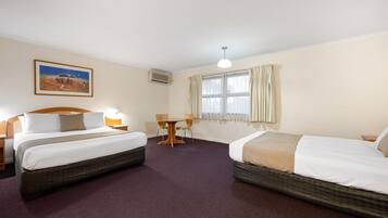 Quarto de hotel com duas camas, uma mesa de jantar e um quadro na parede.